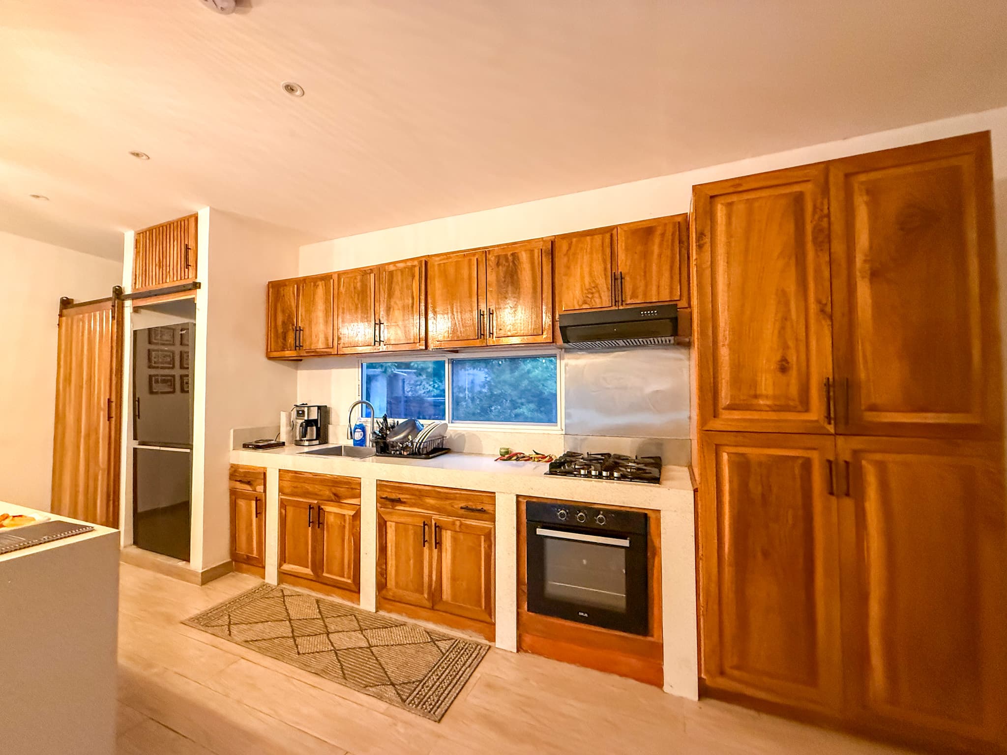 Finished teak kitchen with upper cabinets, a full-height pantry and built-in oven
